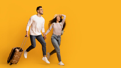 Travel Ad. Excited Young Middle Eastern Couple Running With Suitcase