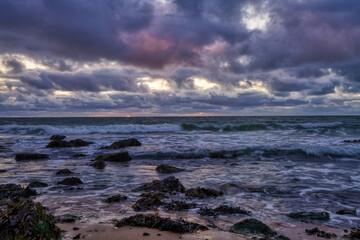 Landscape, seascape sunset on the coast of Huisduinen, the Netherlands. long exposer of waves, dramatic sky, detailed, seaweed, rocks