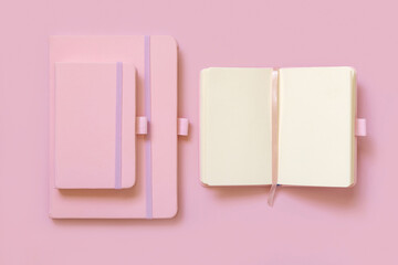 Opened Pink notebook near other two on light pink top view. Textbook mockup