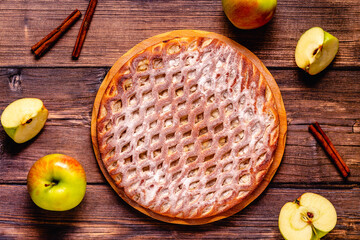 Homemade apple pie with cinnamon on a wooden background.