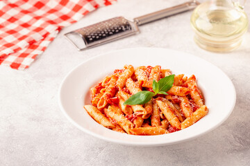 Classic italian pasta penne alla arrabiata with fresh basil on a light background