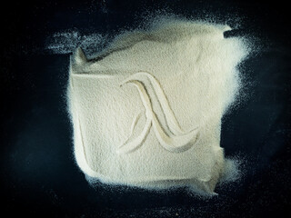 Greek letter lambda written on the white sand with black background