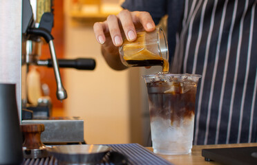 The ballista pours iced American coffee into a cup in the coffee shop to prepare and serve it to customers.