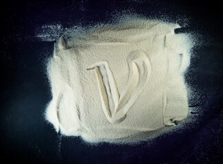 Greek letter nu written on the white sand with black background