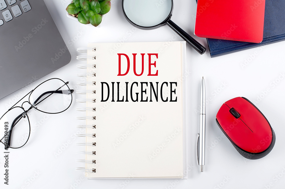 Poster due diligence text on a notepad with laptop on the white background
