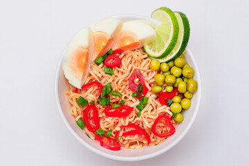 Beautiful Noodle Dish with Green Pea, Eggs, Red Hot Pepper, Greens and Lime on White Background. Instant Noodles