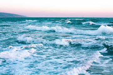 Fototapeta na wymiar Blue foamy sea waves on the beach