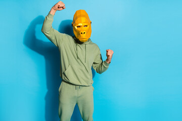 Photo of lucky cool man wear gorilla mask rising fists empty space isolated blue color background