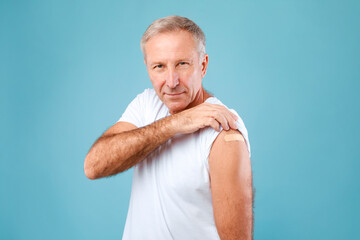 Happy Vaccinated Man Showing Shoulder With Adhesive Bandage