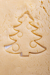 Cooking traditional gingerbread cookies. The shape of a Christmas tree cut from raw dough. Christmas cookies