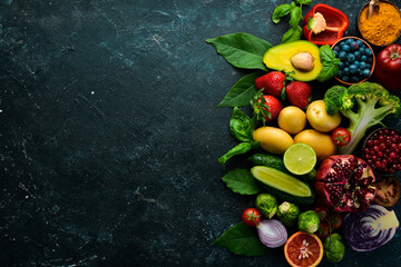 Organic vegan food: fresh vegetables and fruits are good for health. On a black stone background.