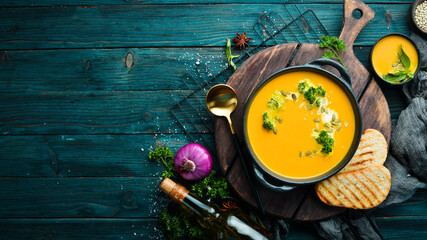 Pumpkin cream soup with pumpkin seeds in a black stone plate. Autumn menu. Diet. Top view. Free space for text.