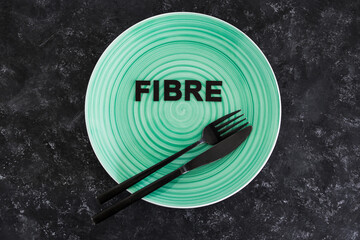 Fibre (uk spelling) text on dining plate with fork and knife, healthy nutrition and research about the microbiome