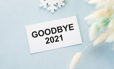 Text Bye Bye 2021 text on a card on a row of snowflakes and dried flower branches