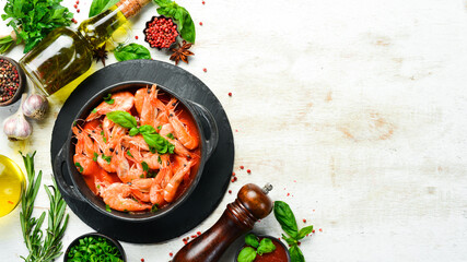 Food. Boiled shrimp in tomato sauce with basil on a black stone plate. Top view. Free space for your text.