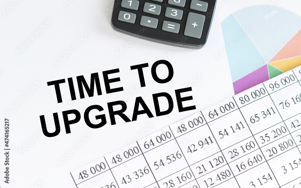 Poster text time to upgrade on notepad next to reports, charts and calculator on your office desk, business