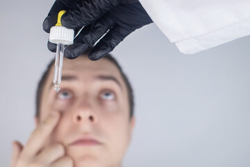 Close-up of eye drops. A man at the doctor appointment, who drips drops into the patient eyes....