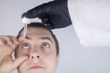 Close-up of eye drops. A man at the doctor appointment, who drips drops into the patient eyes....