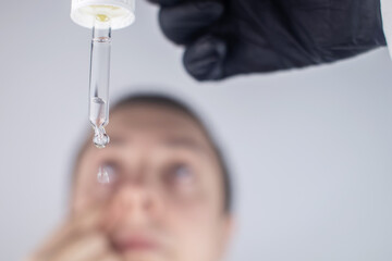 Close-up of eye drops. A man at the doctor appointment, who drips drops into the patient eyes....