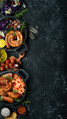 Sausages, baked cabbage, sauerkraut, spices and vegetables. Food. Top view. On a black stone background.