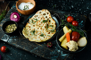 Pita bread with rosemary, Jewish matsa on a plate in the hands of a chef On a black background.