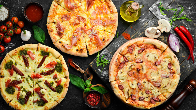 Pizza background. Set of delicious homemade pizzas. On a black background.