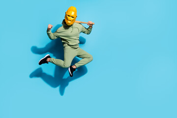 Obraz na płótnie Canvas Photo of astonished batter guy jump hold bat rejoice goal attainment wear gorilla mask isolated blue color background