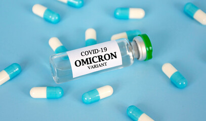New OMICRON variant of Coronavirus COVID-19 in glass bottle with pills around on blue background....
