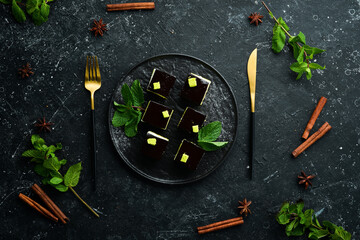Chocolate mousse dessert Opera on a black plate with mint. Top view. Rustic style.