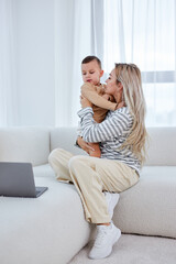 Naklejka na ściany i meble Cute little boy and cuddle pretty young mum show love and affection, beautiful mother and small preschooler son have fun at home embrace sharing close tender moment together. in cozy room