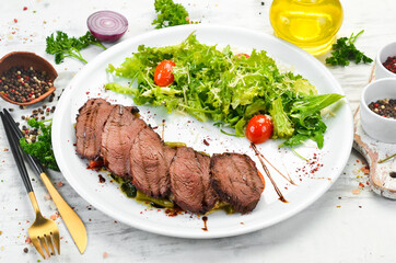 Veal steak with salad and vegetables. On a white background. Top view.