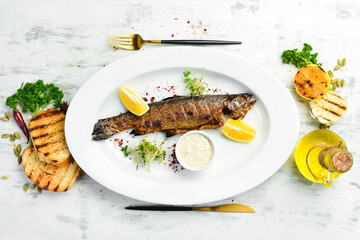 Grilled trout with vegetables on a plate. Seafood on the menu. Top view.