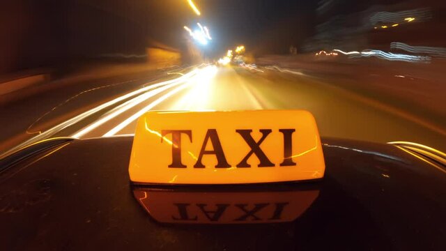 Intercity cab service concept, nightlapse footage of Taxi sign mounted on vehicle rooftop driving