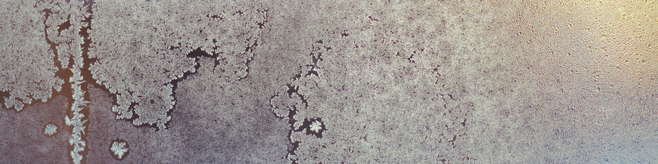 Frozen and misted window glass. Abstract winter banner. Ice crystals and water droplets. End of a frosty day with a low setting sun. Misty and translucent natural headline