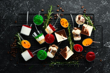 Set of sweet mini desserts in plastic cups. On a black stone background. Top view. Sweet bar.