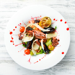 Frutti di mare salad with seafood: shrimp, squid, mussels and octopus. Top view. Rustic style.