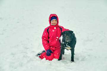 A cheerful girl on a walk with a dog on a winter day