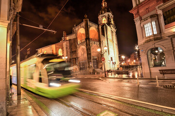 Bilbao tram circulating next to the Ribera market at night and raining