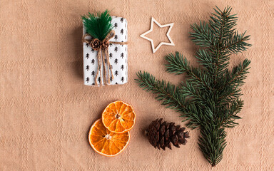 Christmas composition with eco crafted gift, dried orange, cone, xmas tree, gift and wood star. Natural minimal new year concept, top view, isolated, flat lay, copy space on beige background, banner