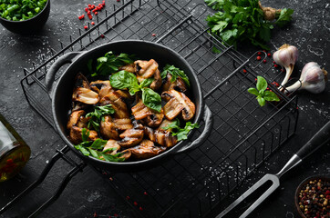 Food. Grilled mushrooms with basil on a black stone plate. Top view. Free space for your text.