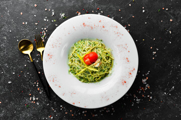 Spaghetti with pesto sauce and parmesan cheese on a white plate. Top view.