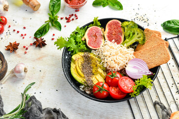 Food. Buddha bowl: noodles with avocado, figs, chia and lettuce in a black stone plate. Top view. Free space for your text.