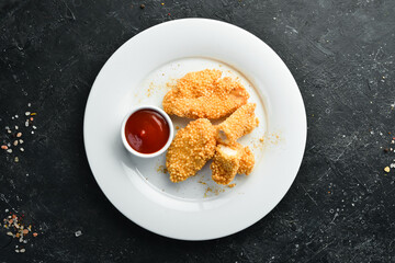 Fried chicken nuggets with ketchup sauce on a plate. Top view.