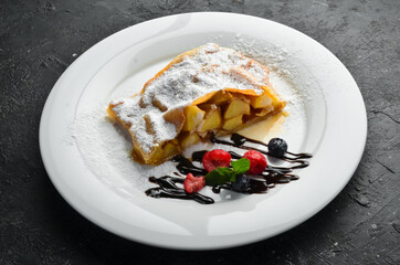 Dessert. Apple strudel with berries and chocolate on a plate. Top view.