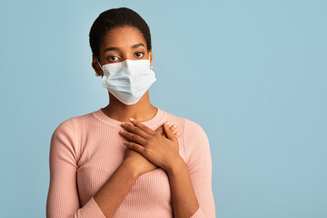 Young Blask Woman In Protective Medical Face Mask Holding Hands On Chest © Prostock-studio