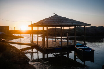 Wooden gazebo on the water at sunset