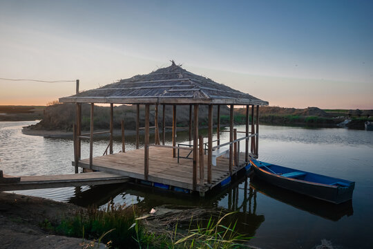 Wooden gazebo on the water at sunset