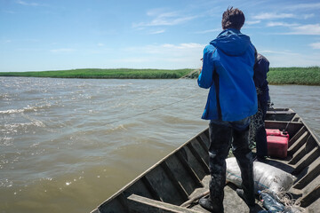 Fishermen get fish with nets from a wooden boat