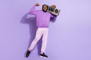 Fototapeta na wymiar Full length body size view of attractive cheerful cool guy holding player showing muscles isolated on violet purple color background