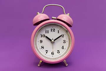 Alarm clock on an isolated minimalistic background in color 17-3938 very peri. Time to look for gifts for loved ones, time to celebrate. The holiday is coming soon. Meet the deadline.